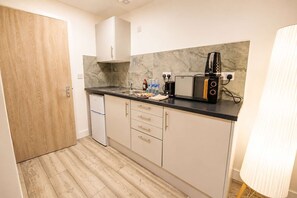 A compact kitchen with a refrigerator, microwave, toaster, and a sink. - Cardiff Studio Getaway: Hot Tub • WIFI (Cardiff)