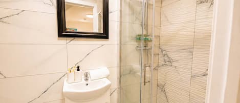 A bathroom with a marble sink, a glass-enclosed shower, and a mirror above the sink.