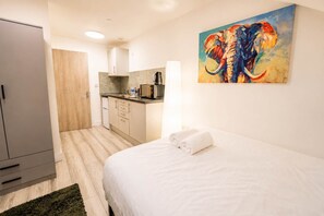 A hotel room with a bed, a painting of an elephant, a kitchenette, and a wardrobe. - Cardiff Studio 9 | Ensuite & Private Kitchen (Cardiff)