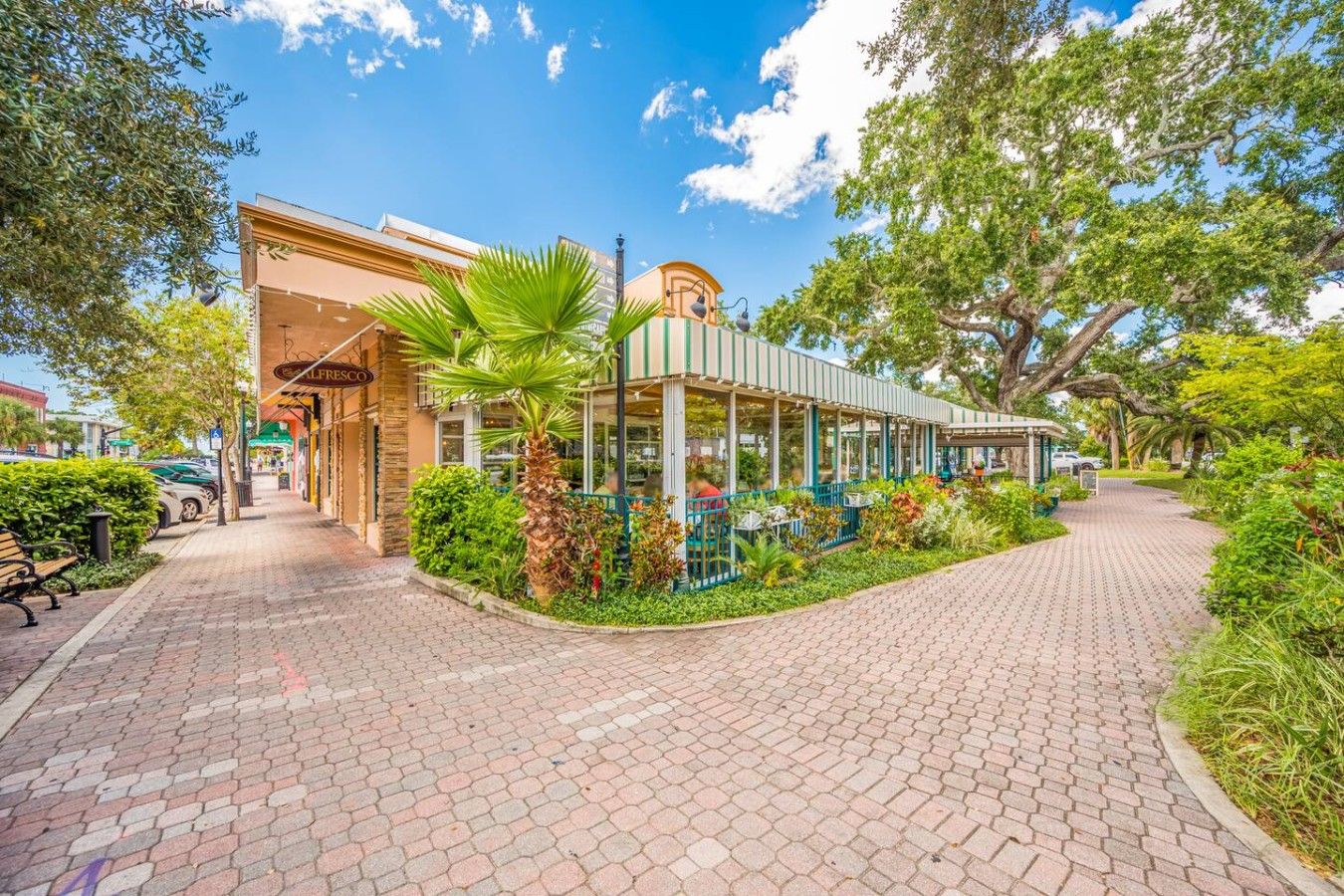 A building with a storefront labeled 'ALBERT'S' and a covered outdoor seating area with tables and chairs.