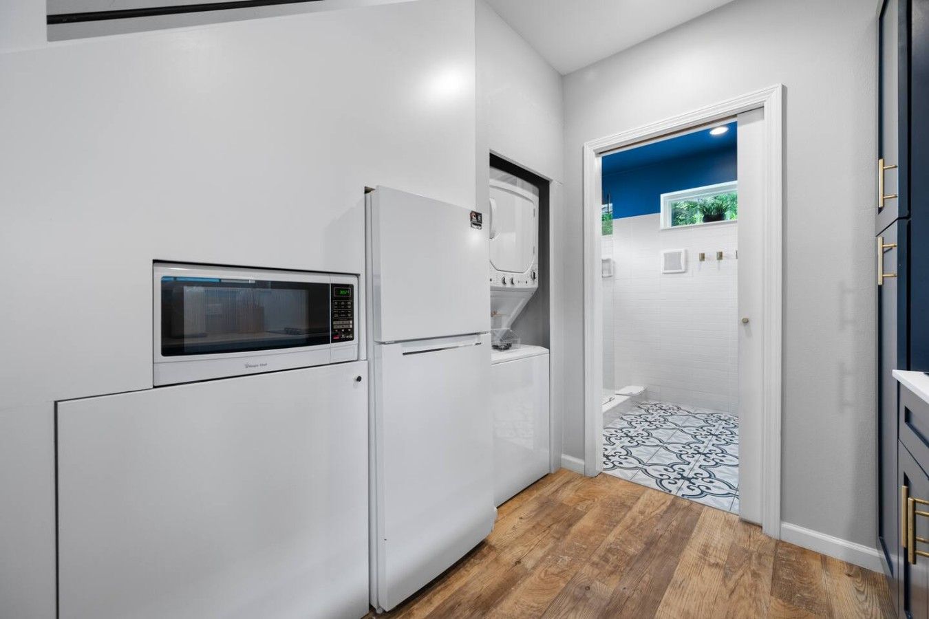 Una cocina compacta equipada con microondas, refrigerador y lavadora.
