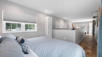A bedroom with a large bed, a bedside table, and a window with blinds.