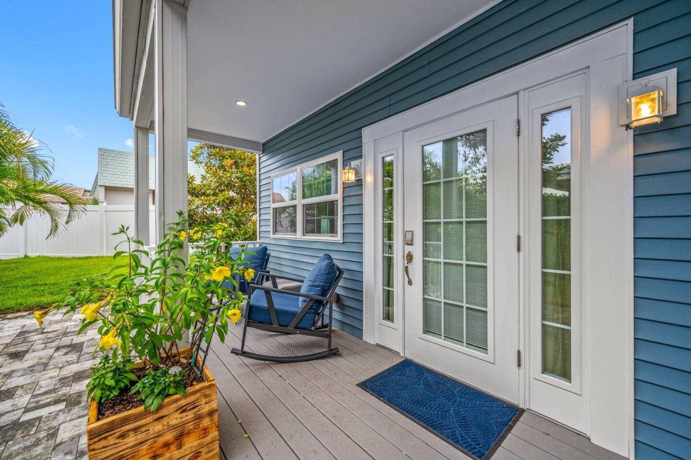 A covered porch with a wooden bench, a potted plant, and a door with a glass panel.