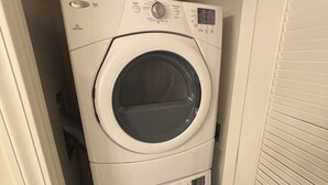 A compact, two-door washer and dryer unit in a narrow hallway.