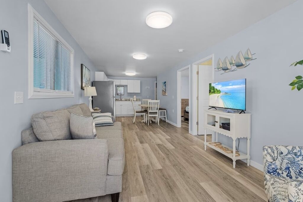 Uma sala de estar moderna com sofá, TV e área de jantar.