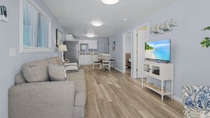 A modern living room with a sofa, TV, and a dining area. - LOCATION!  LOCATION!   Charming 2-bedroom house in delightful Fort Myers Beach (Fort Myers Beach)