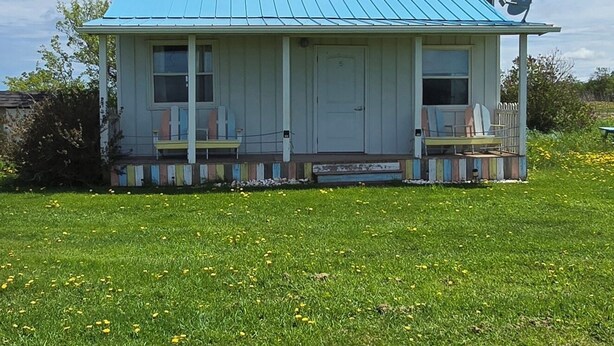 A single-story house with a blue metal roof, a satellite dish, and a number '5' on the door. - Cabin - Older/Simple/Rustic/No Frills/Budget 2 Bedroom - Near Cabot Beach Park (Kensington)