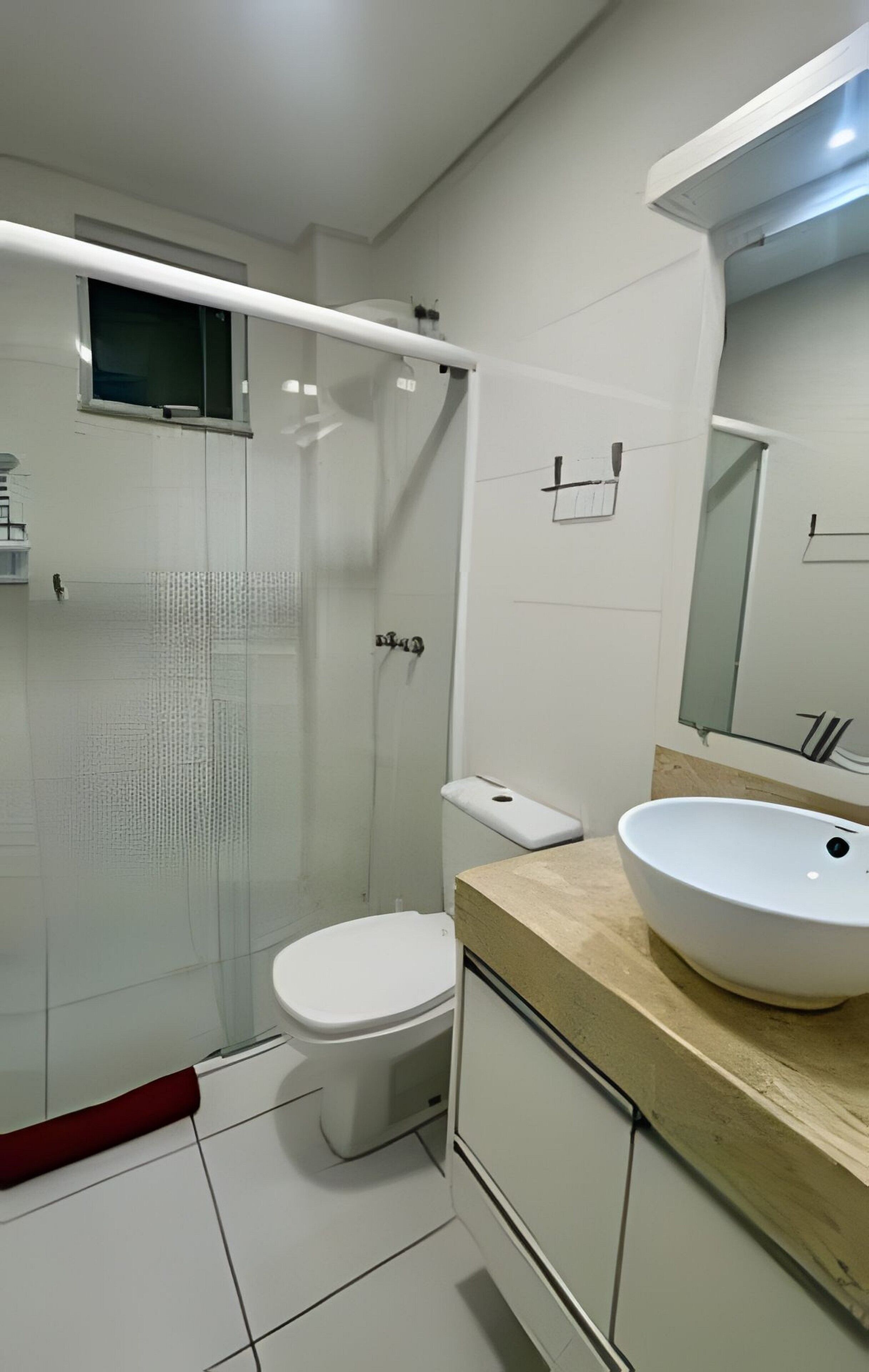 A modern bathroom with a glass-enclosed shower, a white toilet, and a beige countertop with a white sink.