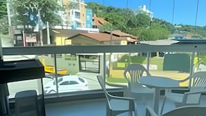 Ein modernes Zimmer mit großem Fenster, weißen Stühlen, einem kleinen Tisch und Blick auf die Stadtlandschaft.