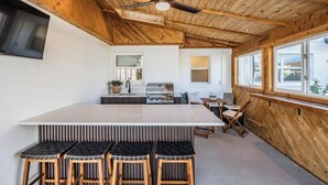A modern kitchen with a wooden ceiling, a central island with bar stools, and large windows providing natural light. - Modern Waterfront Home w/ Pool Near Airport & South Tampa Hotspots (Tampa)