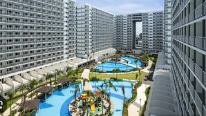 A high-rise hotel with multiple floors, a central swimming pool, and a children's play area. - Timeless Pasay City Apartment for Rent (Pasay)