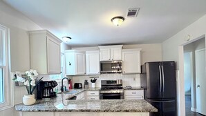 A modern kitchen with white cabinets, a granite countertop, a stainless steel refrigerator, and a built-in oven. - Perfect Location, Minutes to everything Alpharetta & Johns Creek (Alpharetta)