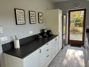 A modern kitchen with a black countertop, white cabinets, a coffee maker, and framed wildlife illustrations on the wall.