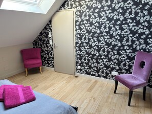 A room with a sloped ceiling, a wardrobe, two chairs, a bed, and a floral wallpaper. - House (12 people) in Jupilles, between Le Mans and Tours, 28km from the Circuit. (Jupillles)