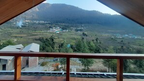 Une vue depuis un balcon en bois, avec une chaîne de montagnes en arrière-plan.
