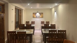 Un espace repas avec des tables et des chaises en bois, un élément décoratif mural et un éclairage encastré au plafond.