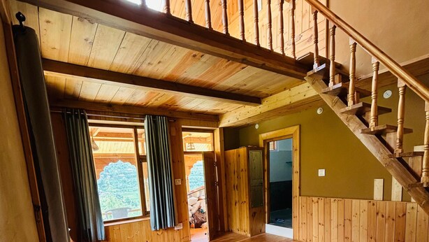 Une pièce en bois avec un lit, un escalier et une vue sur les arbres.