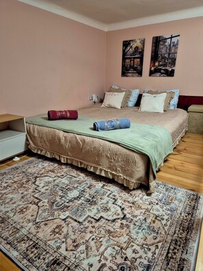 A bedroom with a bed, a bedside table, a wall-mounted power outlet, and a patterned rug. - Cozy 1-bedroom apartment with AC in historic Budapest (Budapest)