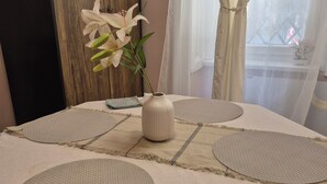 Un lit bien fait, agrémenté d’un vase de fleurs et d’un petit plateau, et offrant une vue sur le feu qui crépite à l’extérieur, à travers de fines rideaux.