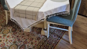 Une table à manger recouverte d’une nappe à carreaux, un vase rempli de fleurs et une bougie.