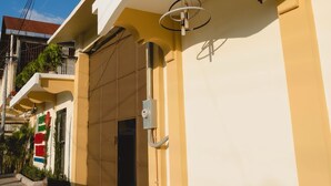 A modern building with a yellow facade, a large garage door, and a security camera. - Hotel & Brunch Lirio de los Valles (Flores)