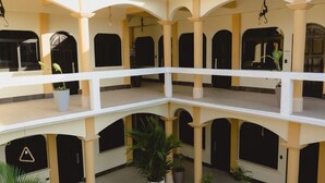 A multi-level courtyard with a central open area surrounded by balconies, potted plants, and a water tank on the roof. - Hotel & Brunch Lirio de los Valles (Flores)