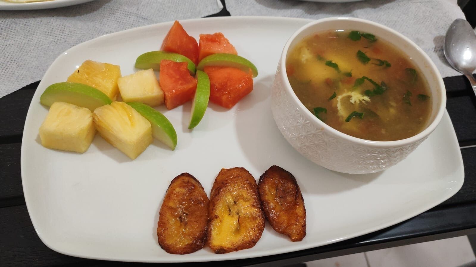 Un plato con frutas cortadas y un tazón de sopa.