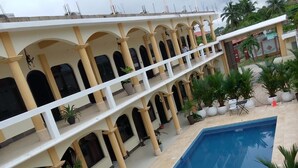 A multi-level building with a swimming pool, outdoor seating, and potted plants. - Hotel & Brunch Lirio de los Valles (Flores)