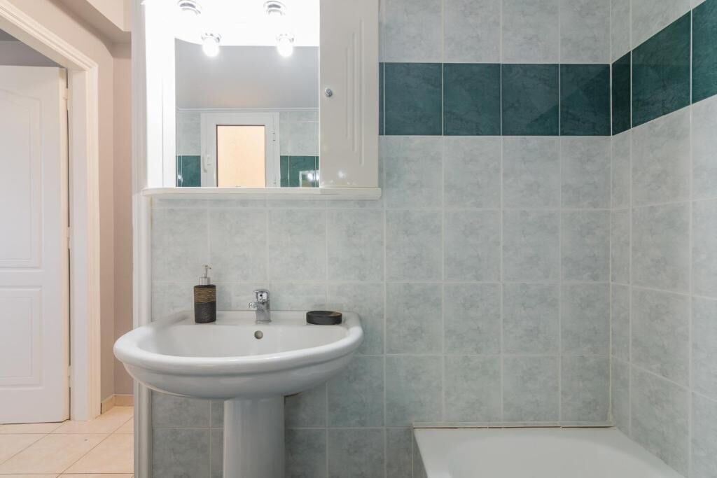 Une salle de bain avec un lavabo blanc, un miroir au-dessus et des toilettes.