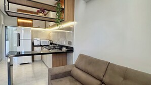 A modern kitchen with a built-in oven, a dining table, and a sofa. - Apartamento Pequi Luxo com Garagem (Palmas)