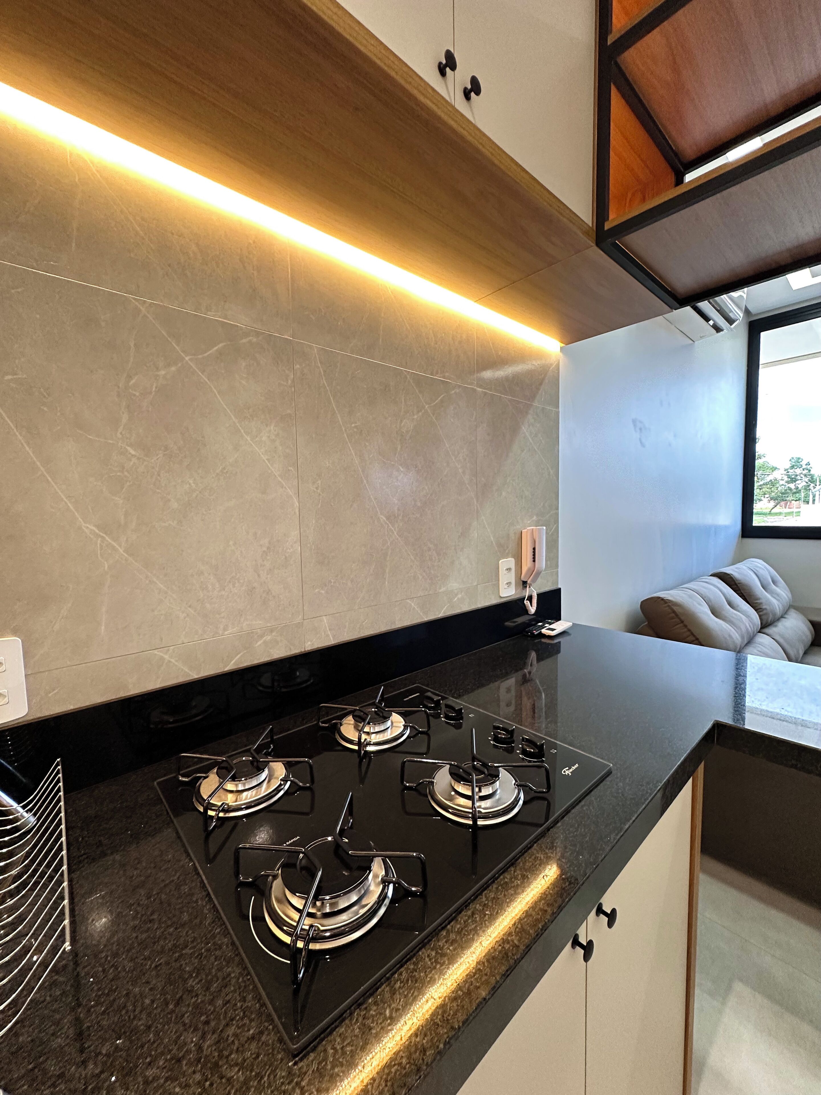A modern kitchen with a black countertop, four burners, and a backsplash.