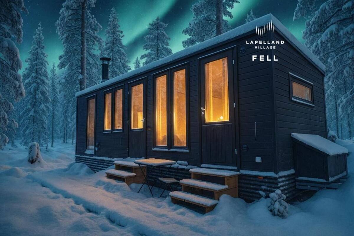 A cabin with large windows, a wooden exterior, and a snow-covered landscape.
