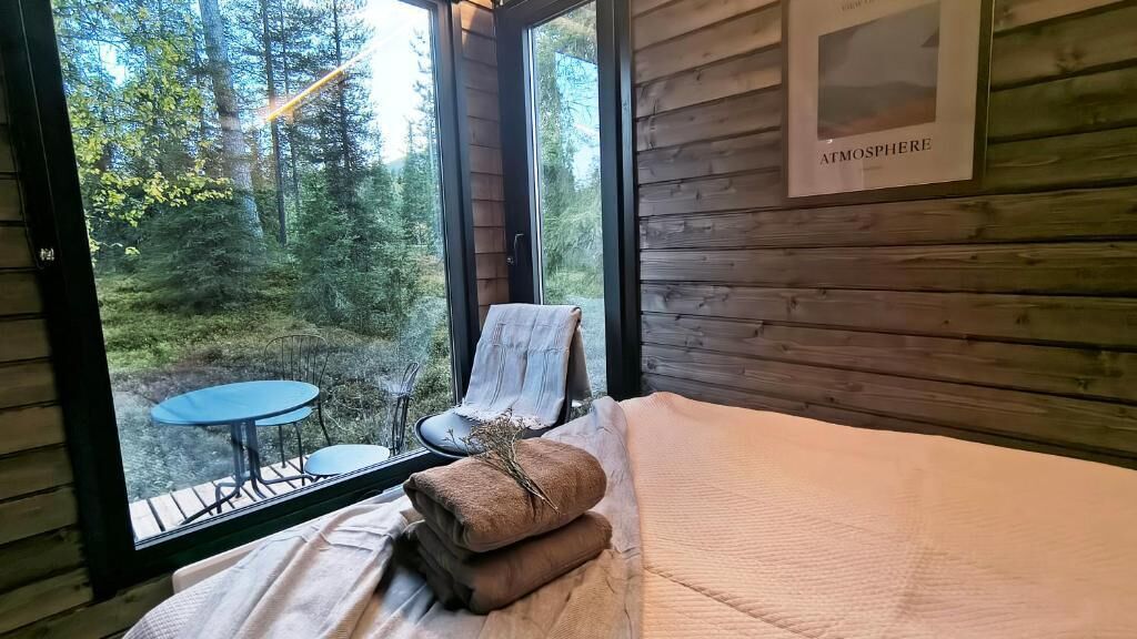 Une pièce de cabane en bois comprenant un lit, une chaise et une petite table.