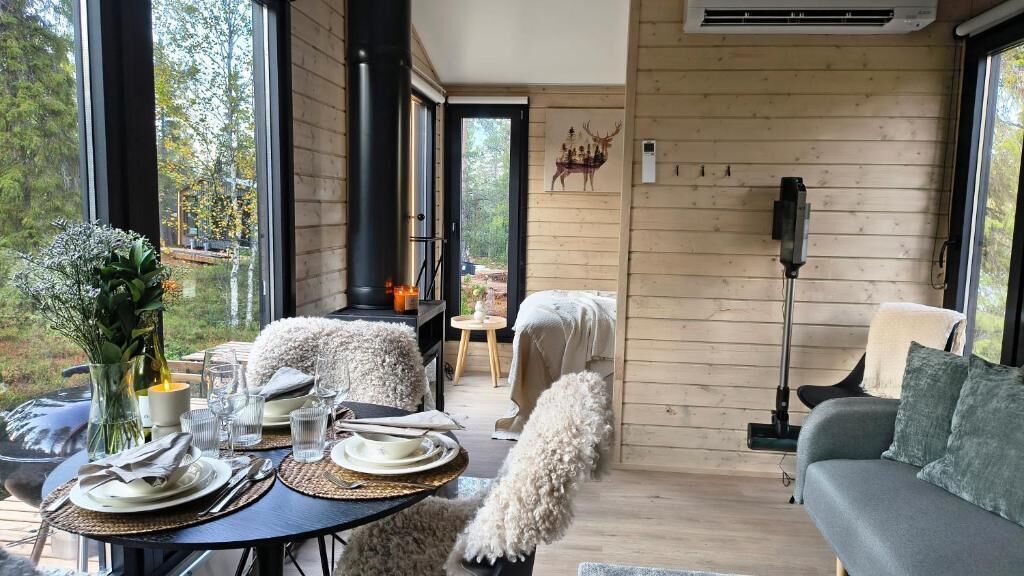 A cozy cabin interior with a dining area, a sofa, and a fireplace.