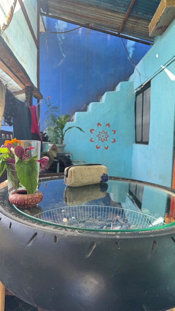 Une table en verre, un sac en fibres tressées et un vase en verre avec des fleurs.
