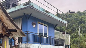 A two-story building with a blue exterior, a balcony, and a water tank on the roof. - Chipaskot Spot (Pokhara)