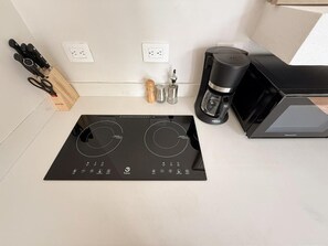 Standaard appartement, uitzicht op tuin | Privékeuken | Een magnetron, een kookplaat, kookgerei, borden en bestek