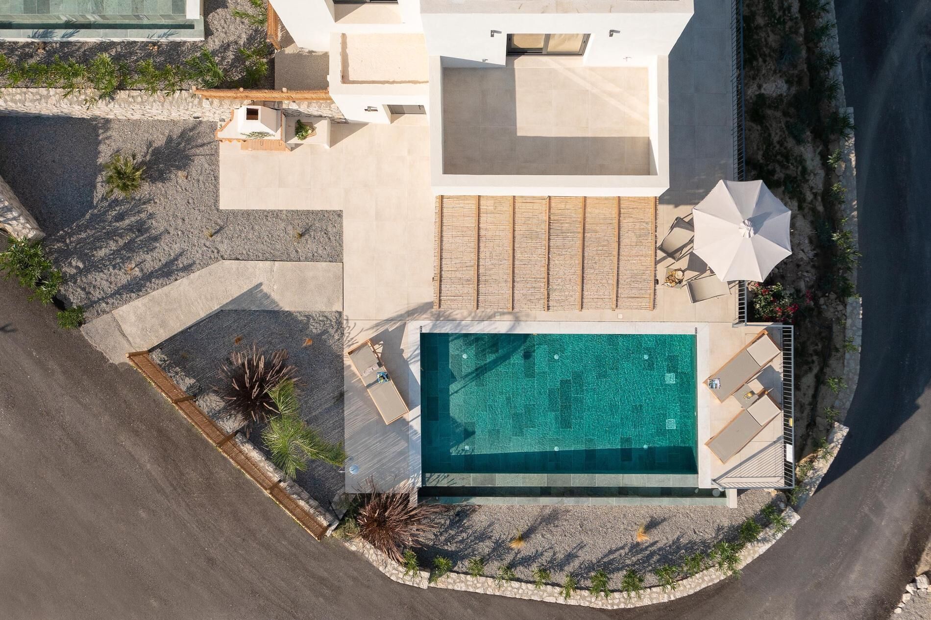 Vue aérienne d’une maison moderne dotée d’une piscine, d’un espace salon extérieur et d’un jardin.