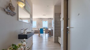 A modern interior with a kitchen area, dining space, and a hallway leading to a door. - Wanderlust by Monholiday (Monopoli)