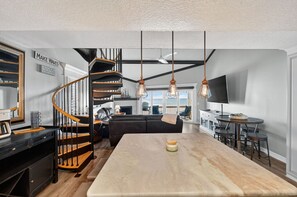 Eine moderne Küche mit einer zentralen Kochinsel, einer Wendeltreppe und einem Essbereich mit Barhocker.