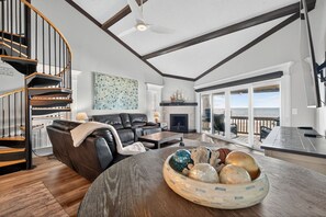 A modern living room with a curved staircase, a fireplace, and a large window overlooking the ocean. - 🌴 Gulf-Front Paradise Awaits in Indian Shores! 🌊 (Indian Shores)