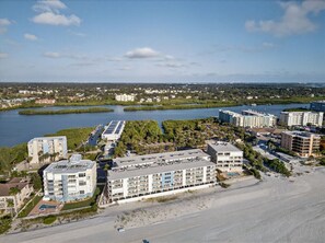 Un hotel frente al mar con varias construcciones, una playa y un puerto deportivo.