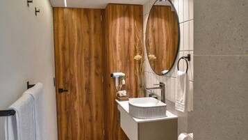 A modern bathroom with a wooden door, a white sink, and a mirror.