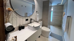 A modern bathroom with a large mirror, white sink, and a walk-in shower. - Mali Experience (Rionegro)
