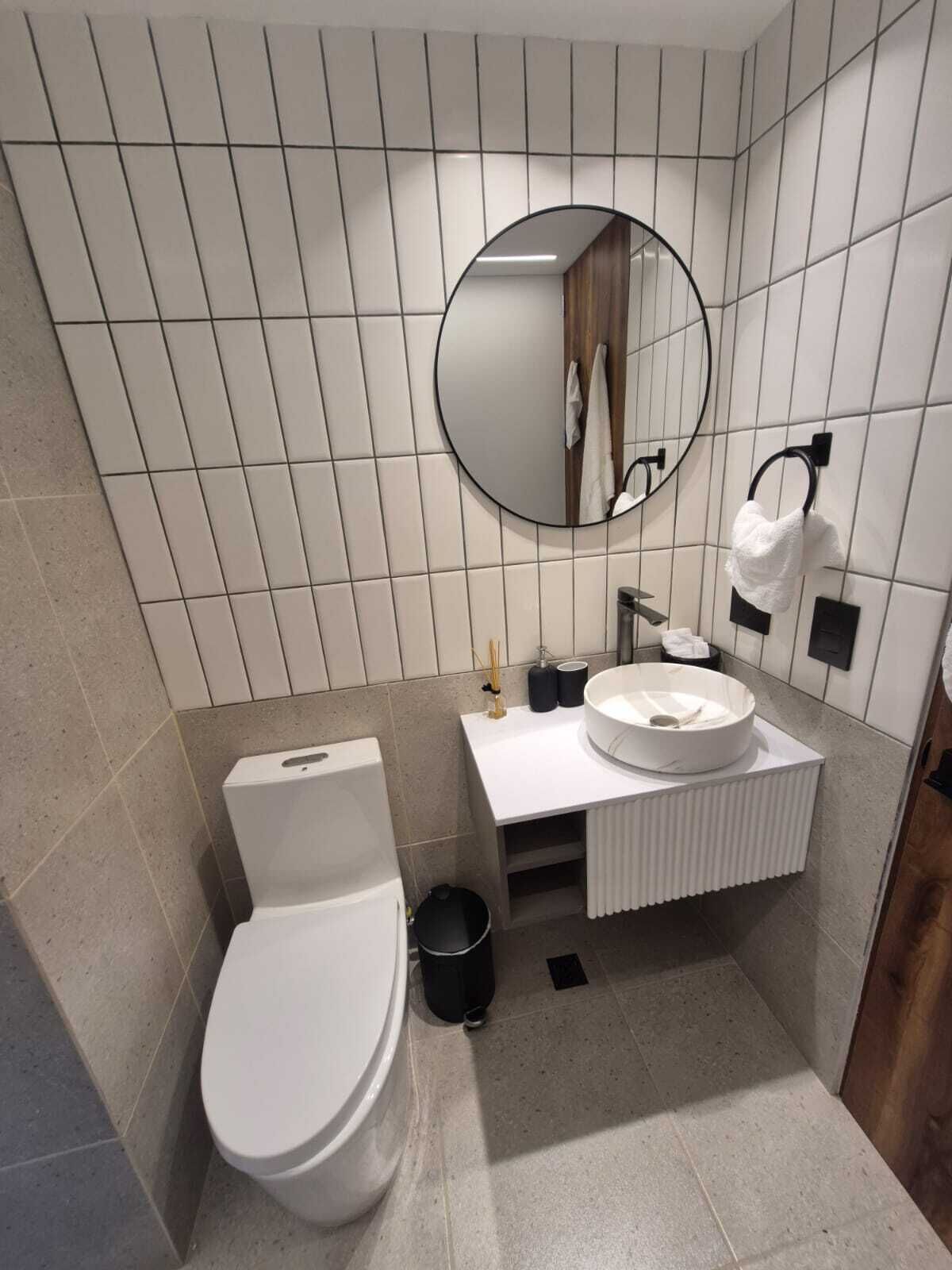 Un baño moderno con inodoro, lavamanos y espejo.
