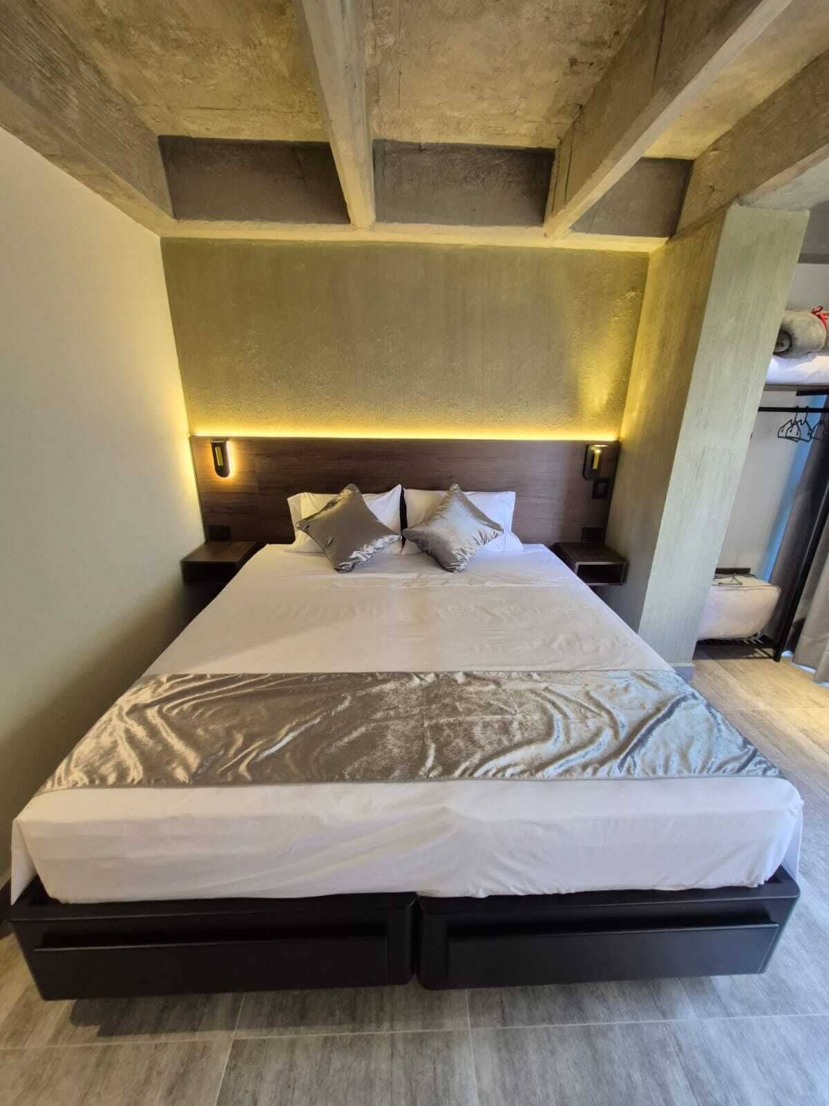 A modern bedroom with a large bed, built-in nightstands, and a headboard with integrated lighting.