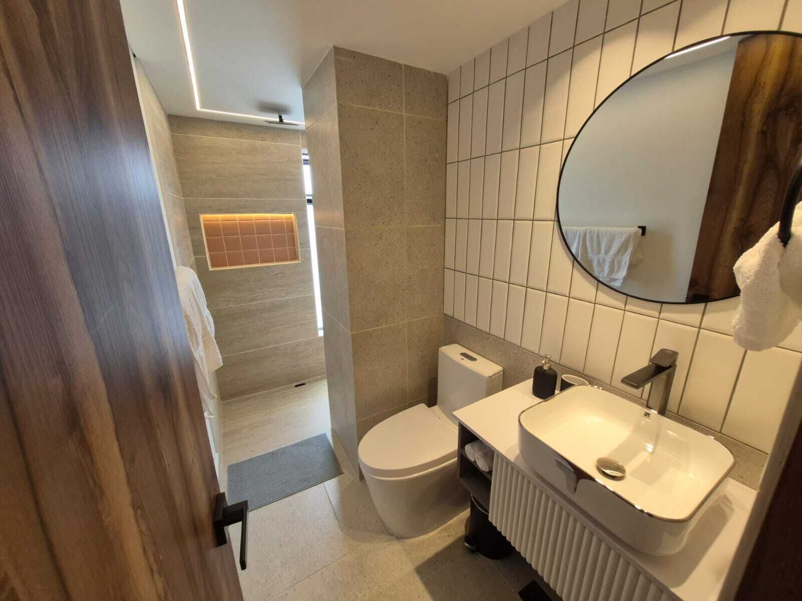 Een moderne badkamer met toilet, wastafel en spiegel.