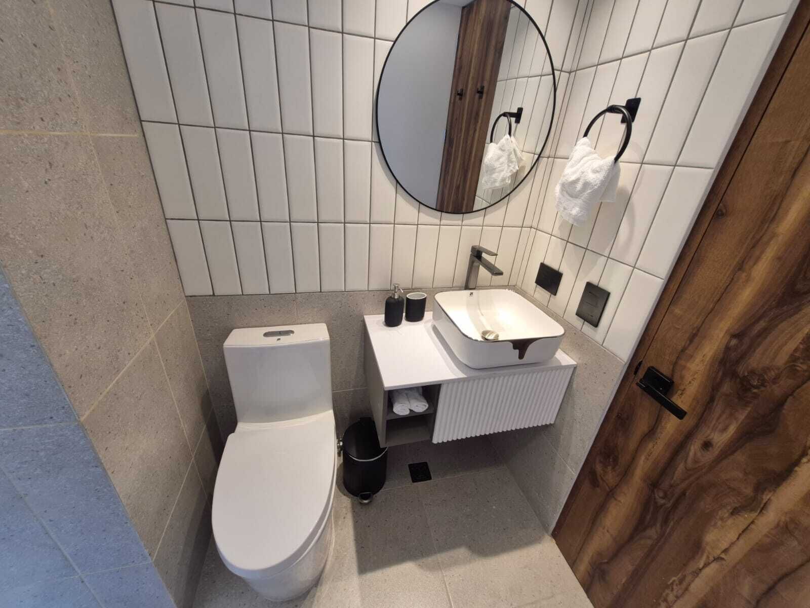 Ein modernes Badezimmer mit Toilette, Waschbecken und Spiegel.