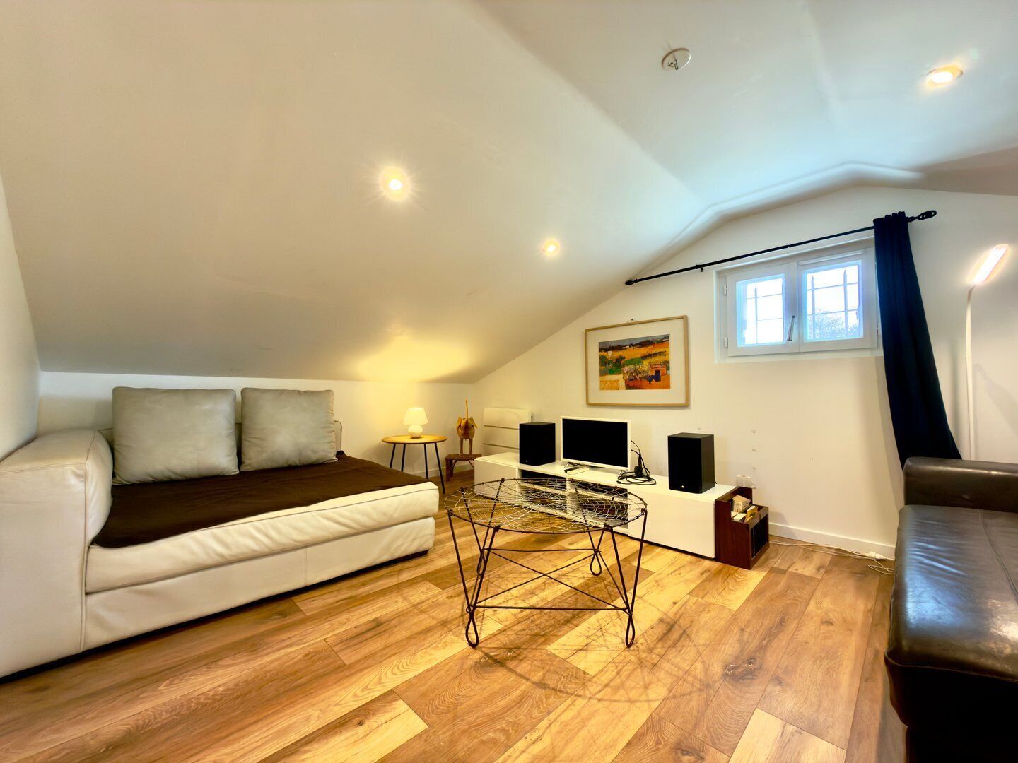Una sala de estar estilo loft acogedora, con un sofá, una mesa de centro y equipo de televisión.