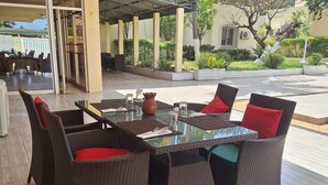 An outdoor seating area with wicker furniture and a glass table. - Hôtel Les Frontières Odienné (Odienné)